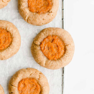 These pumpkin pie cookies are a fantastic Thanksgiving dessert idea! This fall treat features soft and buttery cookies with sweet pumpkin filling. These healthy pumpkin pie thumbprint cookies are also clean eating and low calorie with no refined sugar! Add this simple pumpkin recipe to your Thanksgiving menu and list of healthy baking ideas. They’re a yummy healthy dessert recipe — and easy to make too! The BEST pumpkin cookies!