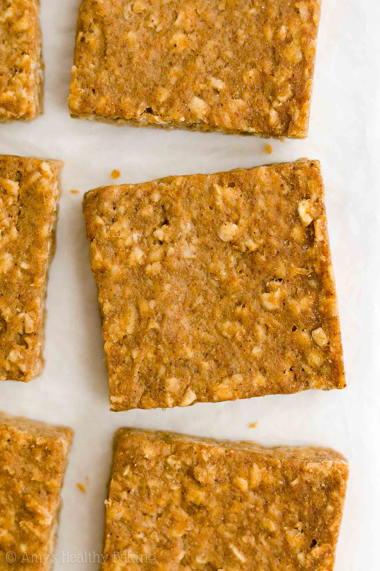 overhead view of healthy pumpkin oatmeal bars on white parchment paper – easy oat bars recipe for breakfasts and snacks – vegan, gluten free, egg free, dairy free, and clean eating with whole wheat and gluten free options – made with oats, pumpkin, spices, and no refined sugar