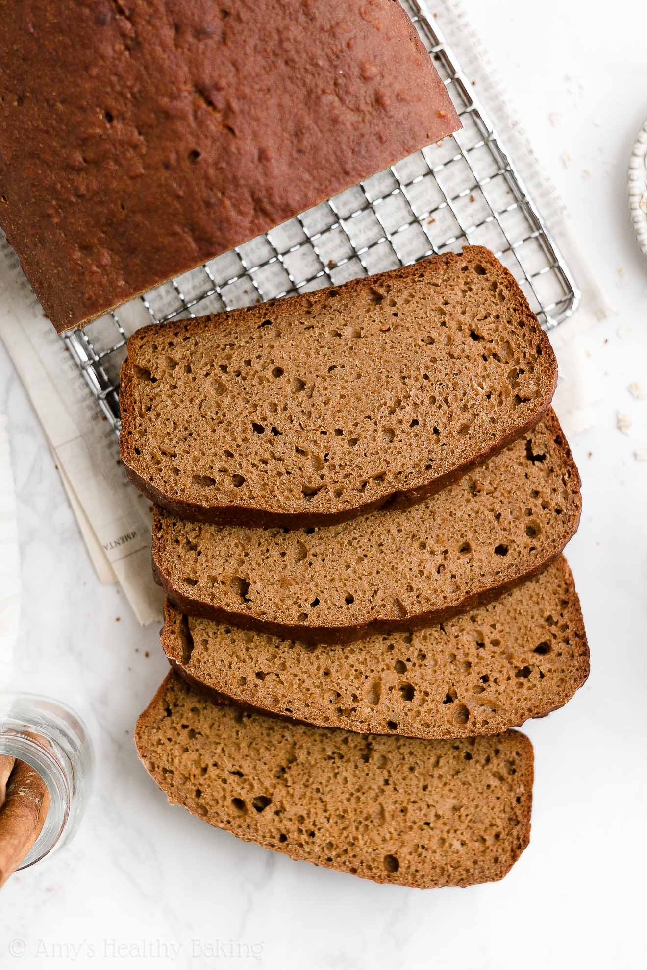 four slices of a healthy oatmeal gingerbread loaf resting on a white marble counter – easy gingerbread quick bread recipe – soft, moist, low fat, low calorie, and clean eating with whole wheat and gluten free options – made with oats, Greek yogurt, molasses, and no refined sugar
