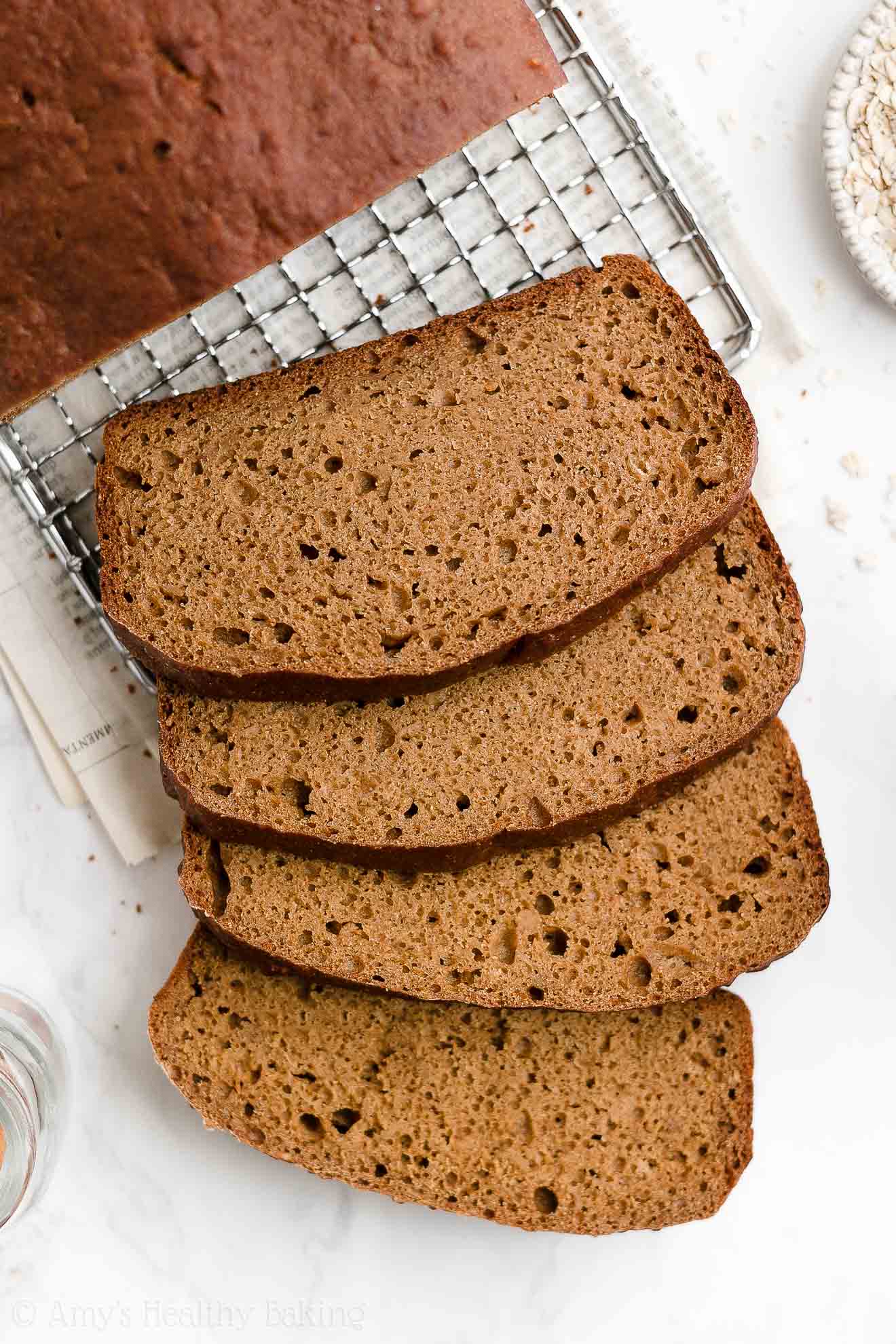 overhead view of four healthy oatmeal gingerbread loaf slices tumbling down off of a wire cooling rack – easy gingerbread quick bread recipe – soft, moist, low fat, low calorie, and clean eating with whole wheat and gluten free options – made with oats, Greek yogurt, molasses, and no refined sugar