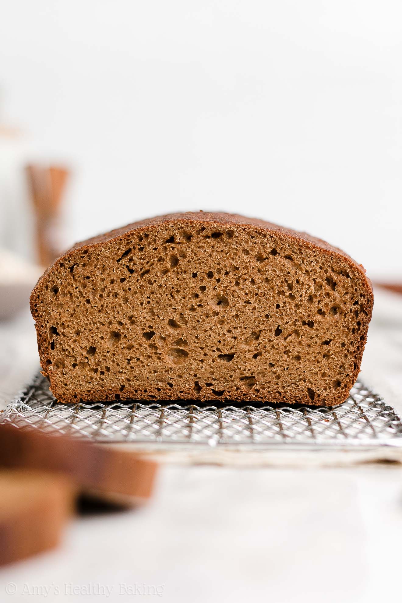 a sliced healthy oatmeal gingerbread loaf sitting on a wire cooling rack with two slices partially visible in the foreground – easy gingerbread quick bread recipe – soft, moist, low fat, low calorie, and clean eating with whole wheat and gluten free options – made with oats, Greek yogurt, molasses, and no refined sugar