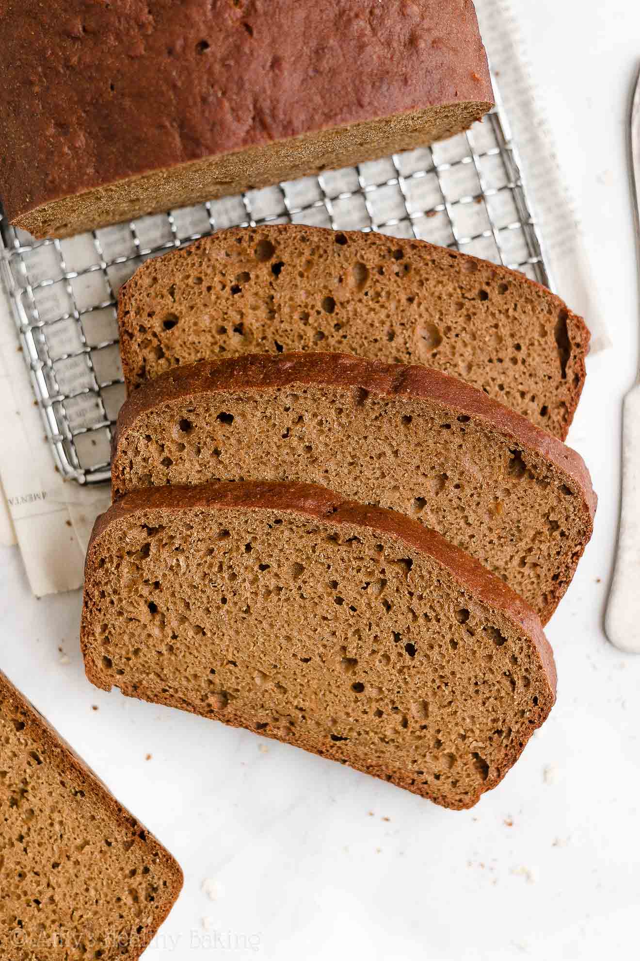three slices of a healthy oatmeal gingerbread loaf on a white marble countertop – easy gingerbread quick bread recipe – soft, moist, low fat, low calorie, and clean eating with whole wheat and gluten free options – made with oats, Greek yogurt, molasses, and no refined sugar