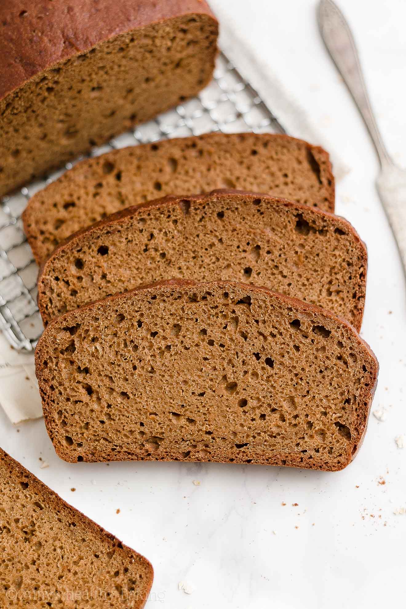 three slices of healthy oatmeal gingerbread loaf resting in front of the rest of the loaf – easy gingerbread quick bread recipe – soft, moist, low fat, low calorie, and clean eating with whole wheat and gluten free options – made with oats, Greek yogurt, molasses, and no refined sugar