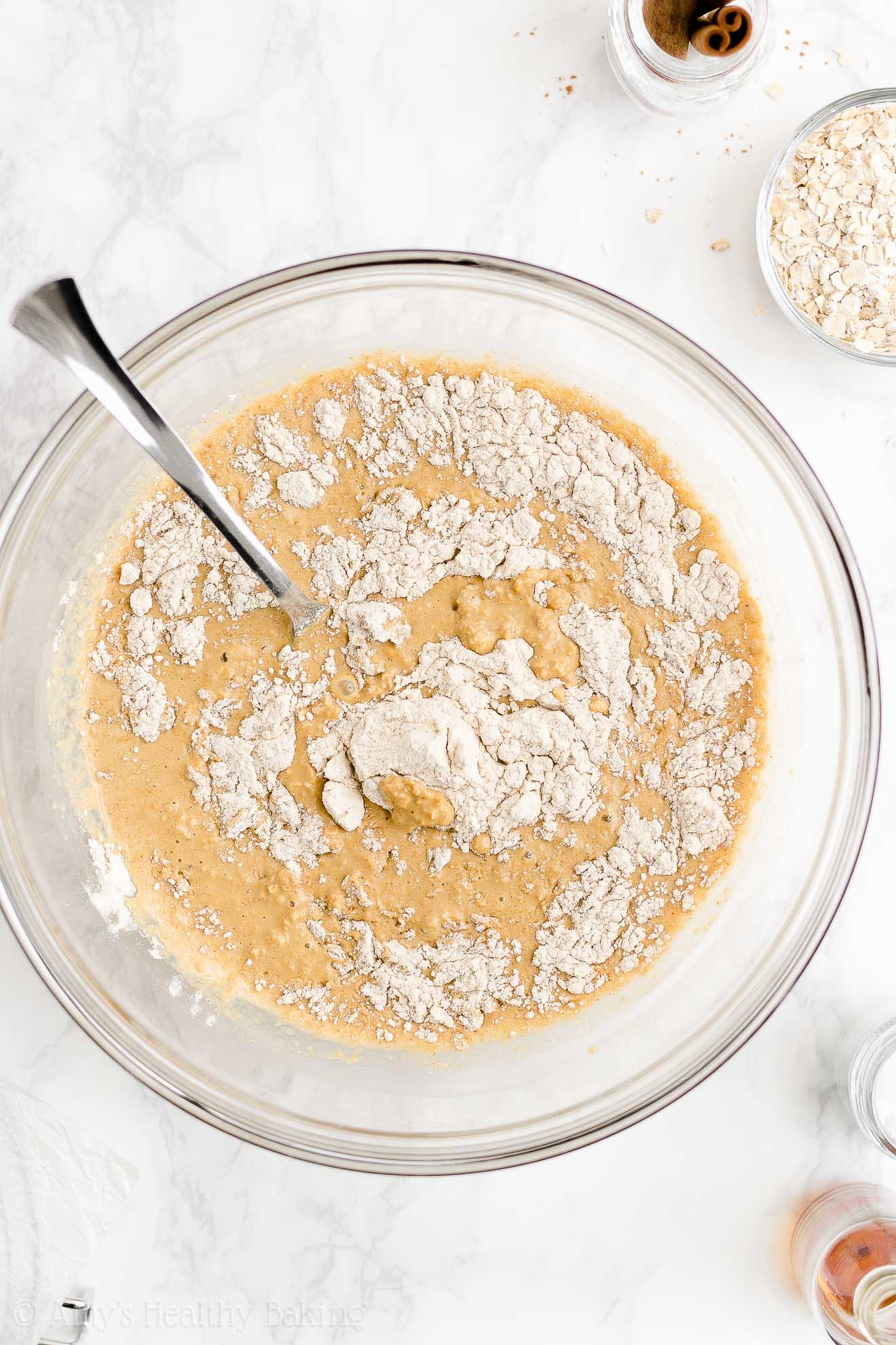 a glass mixing bowl holding a fork and the partially stirred batter used to make a healthy oatmeal gingerbread loaf – easy gingerbread quick bread recipe – soft, moist, low fat, low calorie, and clean eating with whole wheat and gluten free options – made with oats, Greek yogurt, molasses, and no refined sugar