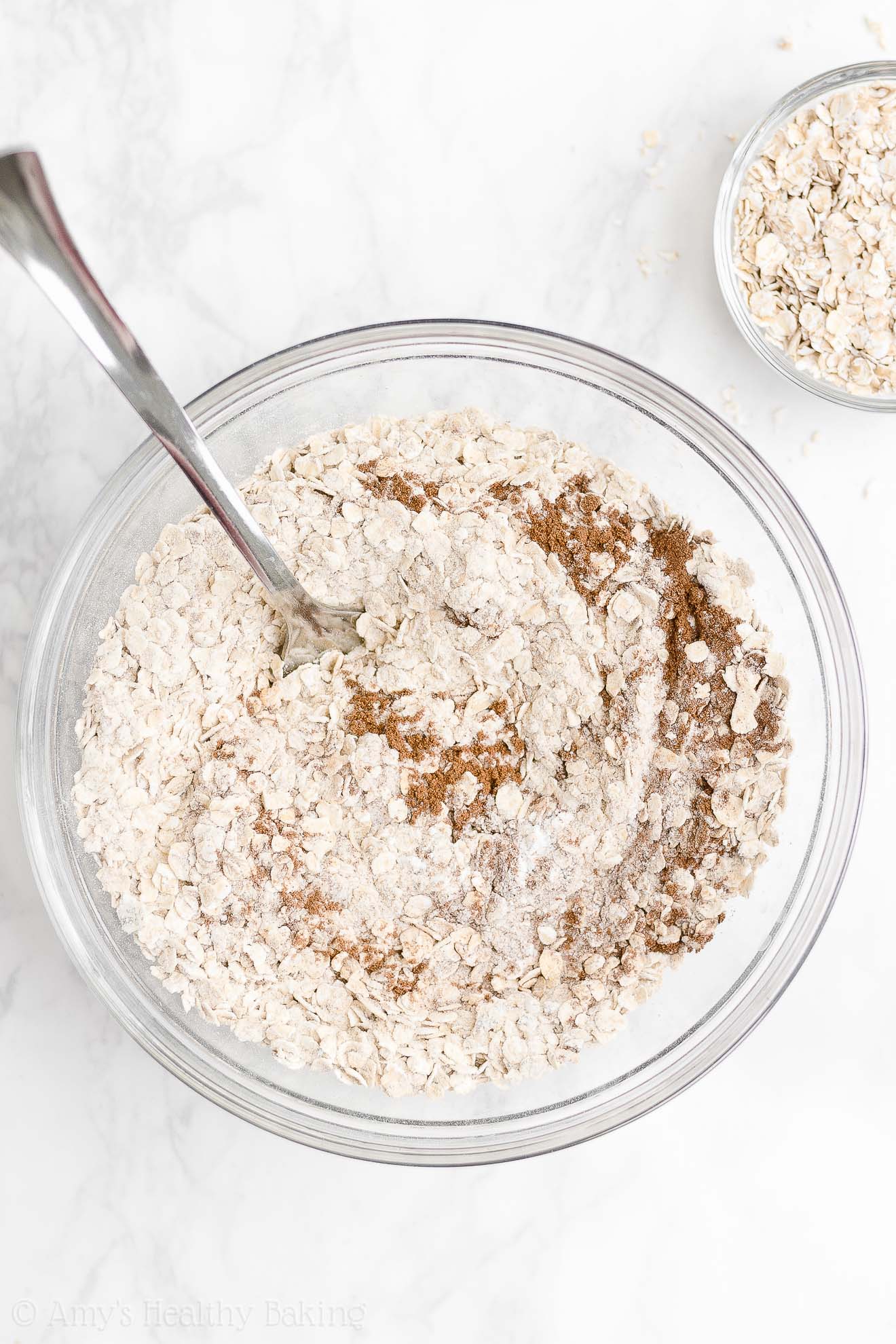 glass bowl holding a fork and the the partially mixed dry ingredients used to make healthy strawberry oatmeal breakfast cookies – easy strawberry breakfast cookies recipe – soft, chewy, low calorie, low fat, and clean eating with whole wheat, gluten free, dairy free, and nut free options – made with oats, fresh strawberries, pure maple syrup, and no refined sugar