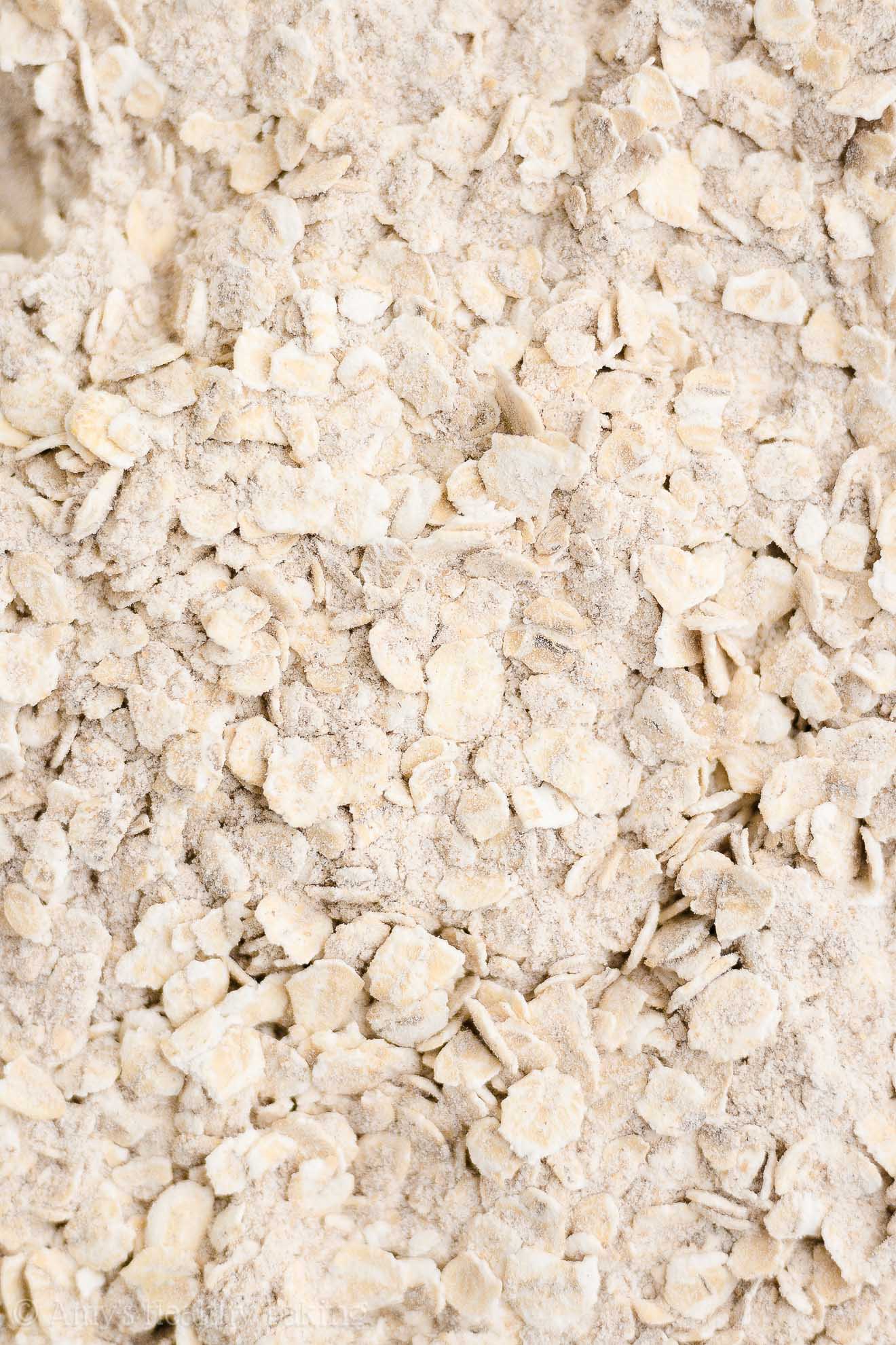 extreme close-up of the freshly mixed dry ingredients used to make healthy strawberry oatmeal breakfast cookies – easy strawberry breakfast cookies recipe – soft, chewy, low calorie, low fat, and clean eating with whole wheat, gluten free, dairy free, and nut free options – made with oats, fresh strawberries, pure maple syrup, and no refined sugar