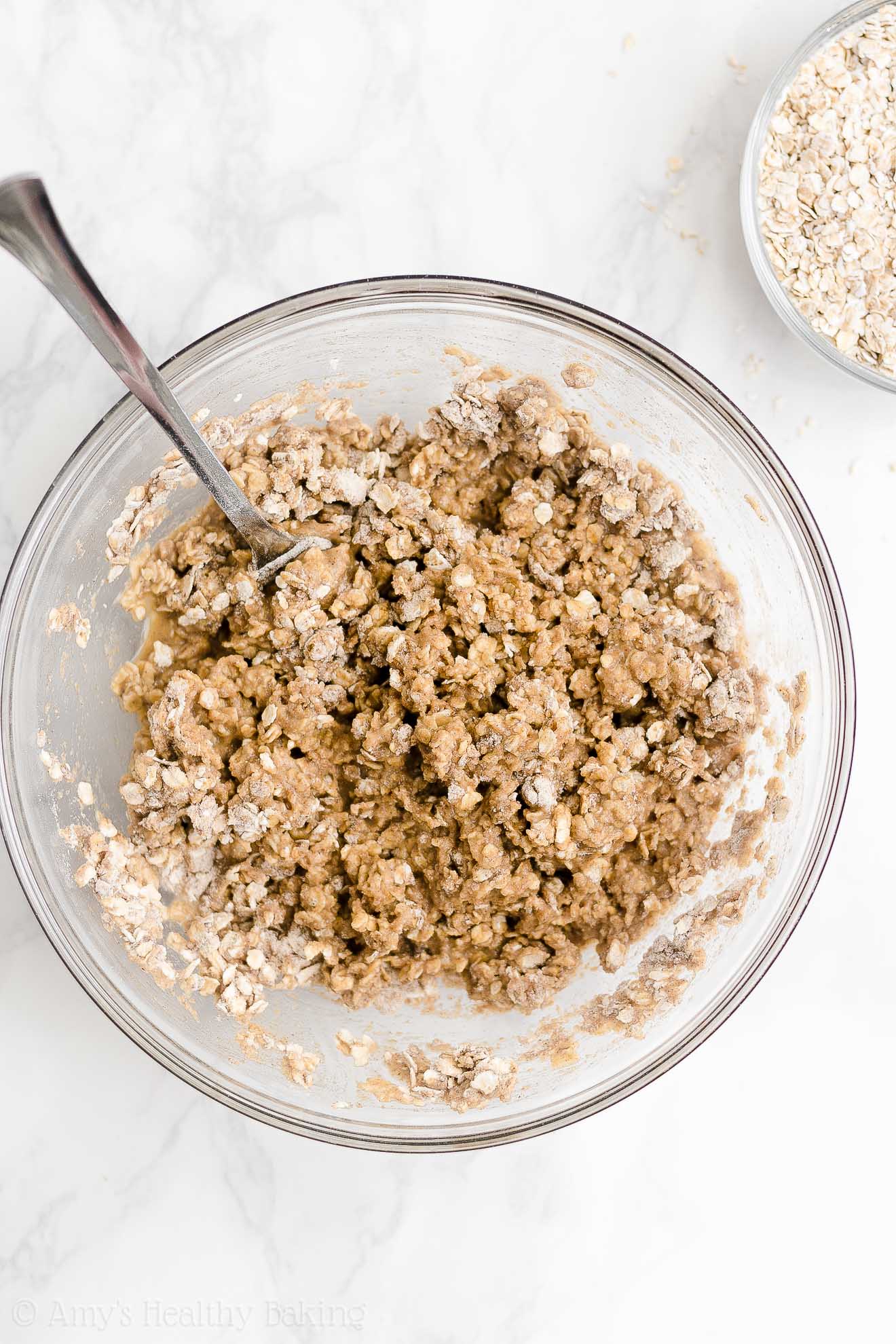 glass bowl holding a fork and the mostly mixed ingredients used to make healthy strawberry oatmeal breakfast cookies – easy strawberry breakfast cookies recipe – soft, chewy, low calorie, low fat, and clean eating with whole wheat, gluten free, dairy free, and nut free options – made with oats, fresh strawberries, pure maple syrup, and no refined sugar